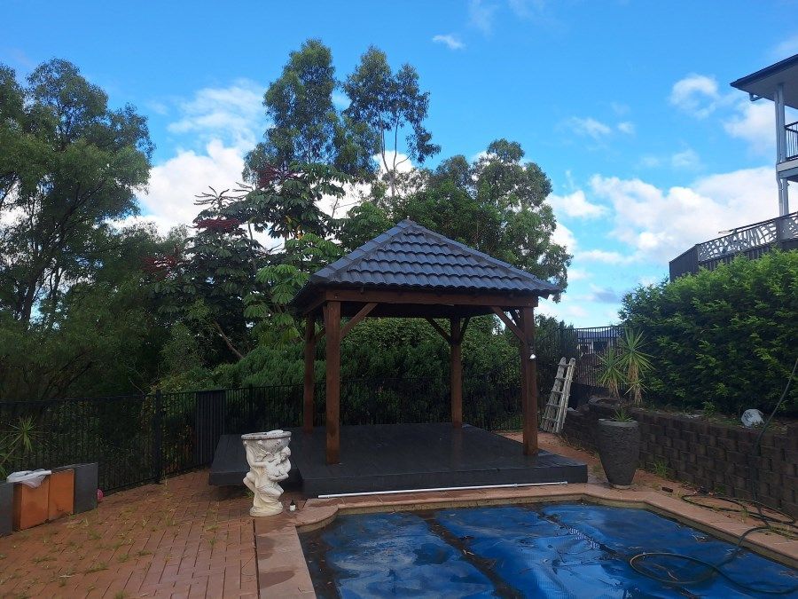 A Gazebo is Sitting Next to a Swimming Pool — Roofing Gold Coast in Tallebudgera, QLD
