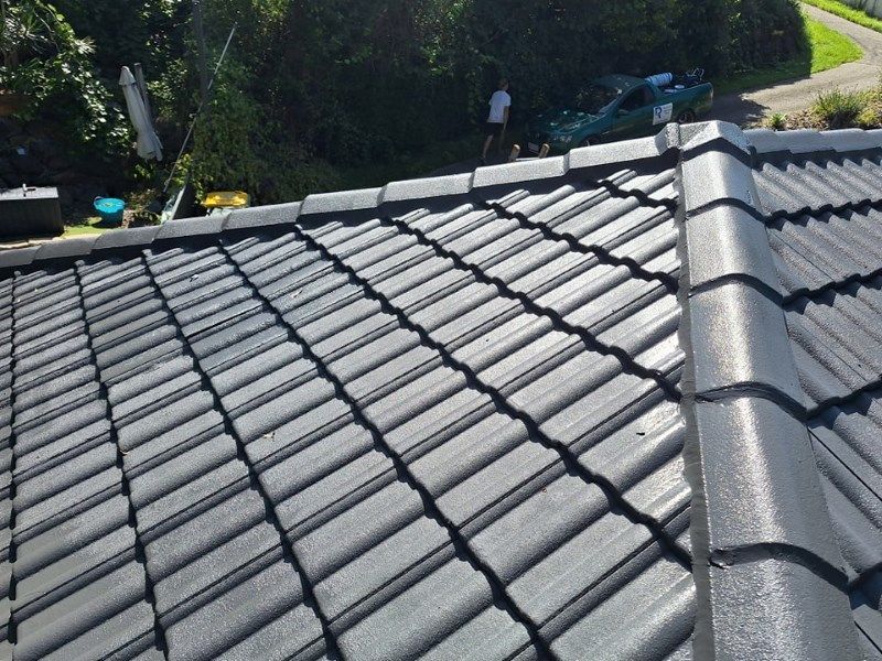 A Man is Standing on the Roof of a House — Roofing Gold Coast in Tallebudgera, QLD
