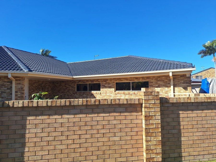 A House With a Brick Wall in Front of It — Roofing Gold Coast in Tallebudgera, QLD