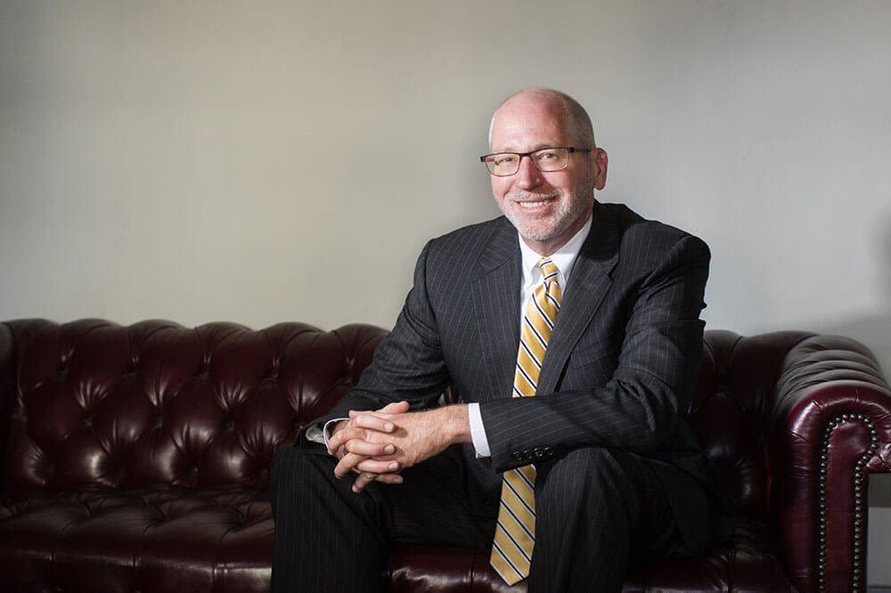 A man in a suit and tie is sitting on a couch.