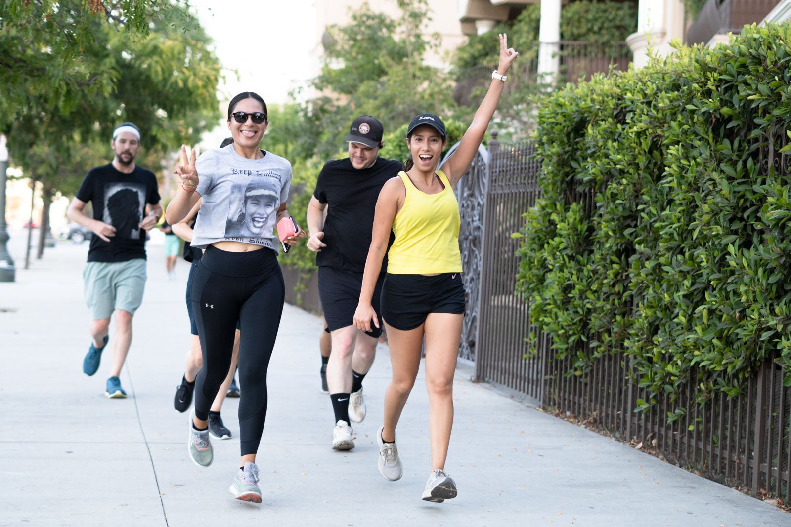 Group of runners on a sidewalk passing by the camera with excitement during a workout