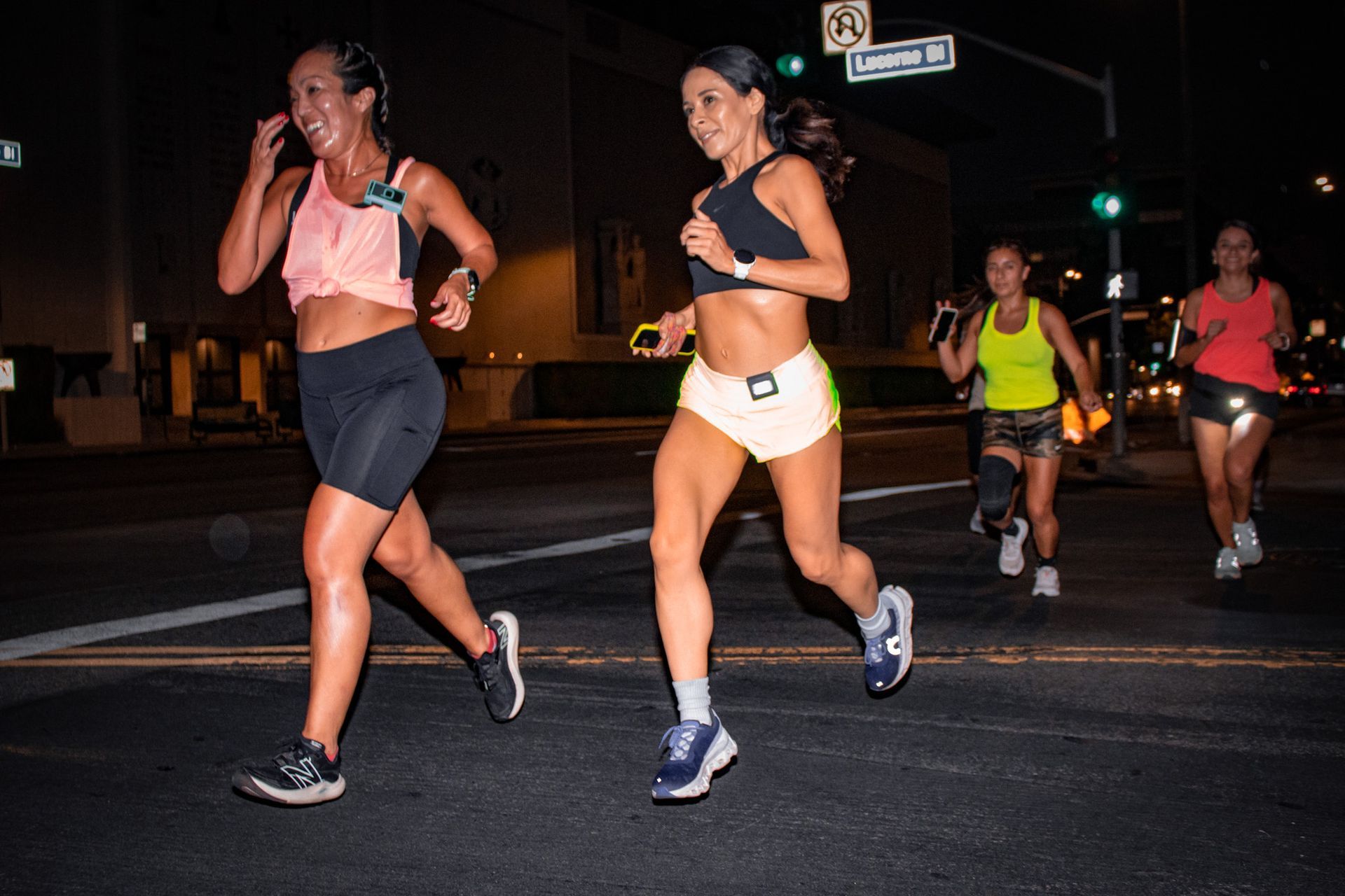 A group of women are running down a street at night.