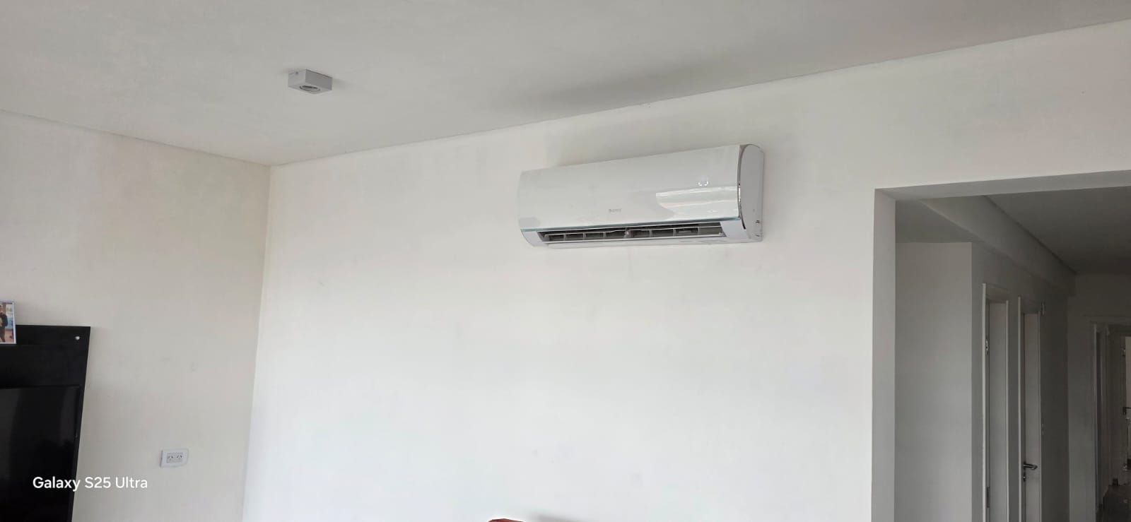 Pared blanca con una unidad de aire acondicionado y una puerta.