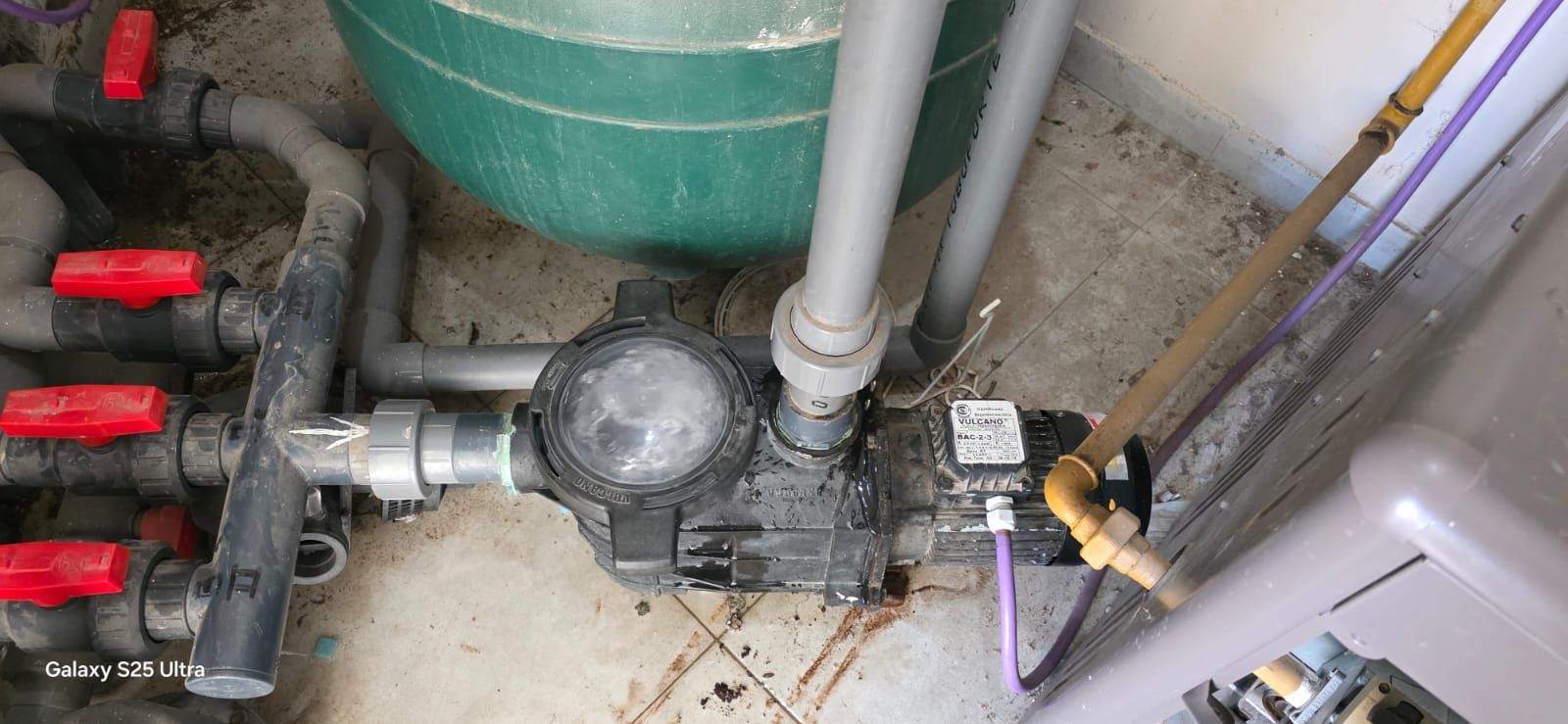 El equipo de la piscina, incluidas las tuberías, las válvulas y un filtro, se instala sobre una superficie de hormigón.