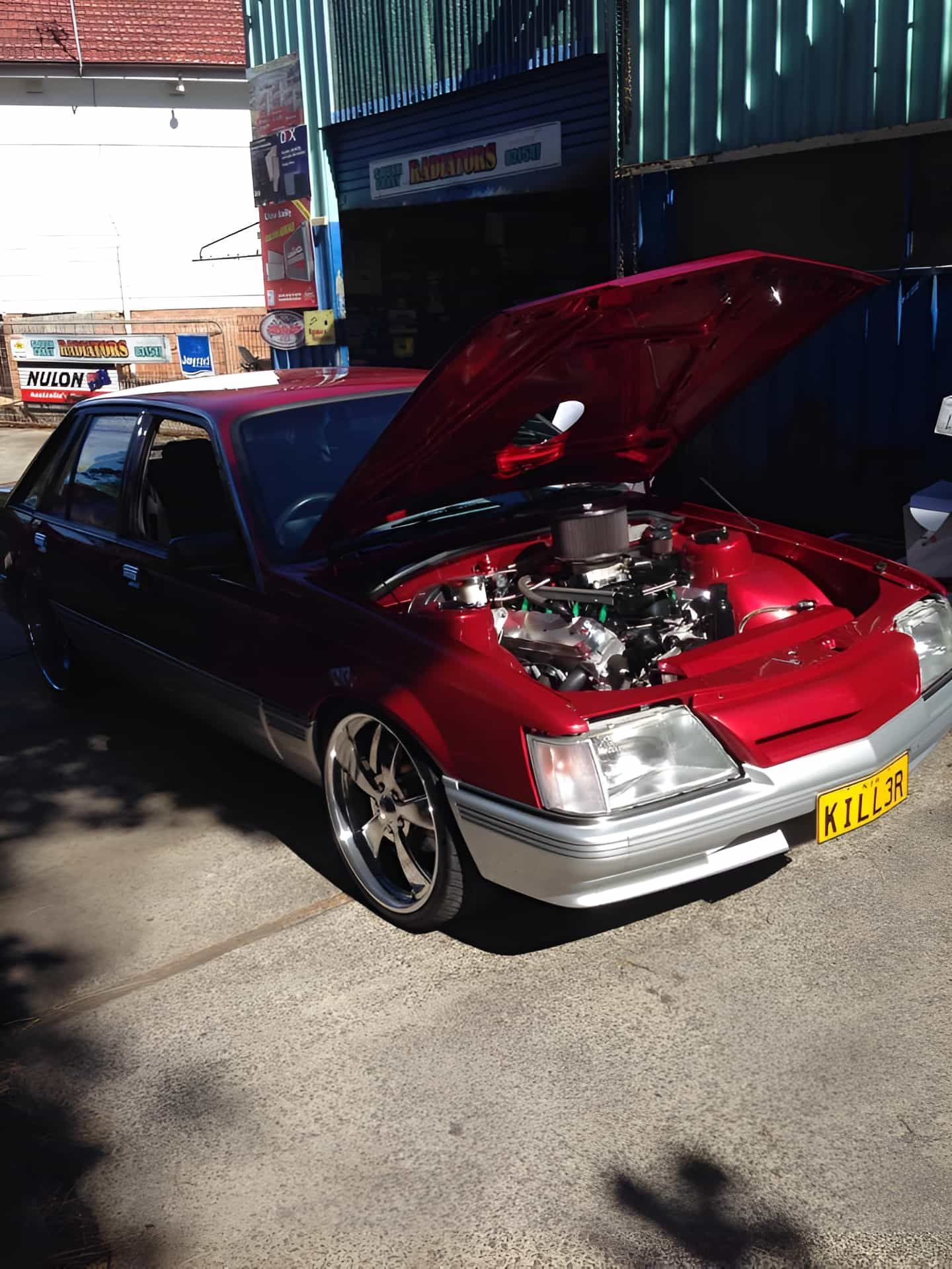 A Red Car With the Hood Up is Parked in Front of a Building — South Coast Radiators In Woonona, NSW