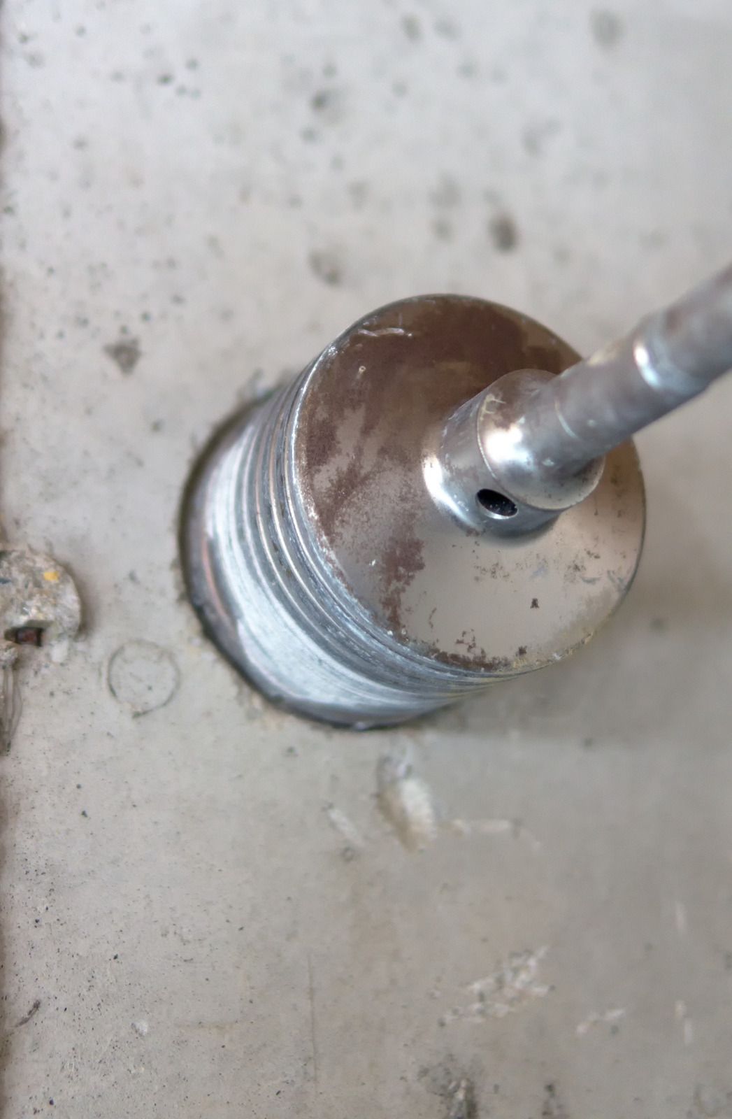 A drill bit drilling into a concrete surface, creating a circular hole.