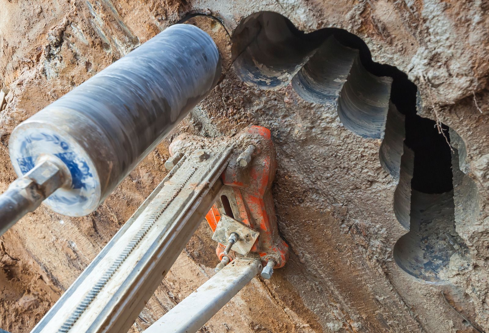 Core drill cutting into a concrete wall, revealing a large hole.