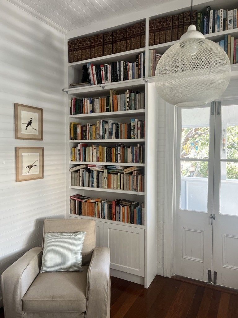 Living Room With a Chair and Bookshelves Filled With Books — D Hinged Kitchens & Joinery in Mullumbimby, NSW