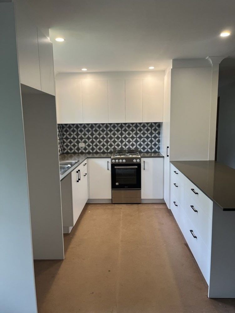 An Empty Kitchen With White Cabinets and Stainless Steel Appliances — D Hinged Kitchens & Joinery in Mullumbimby, NSW