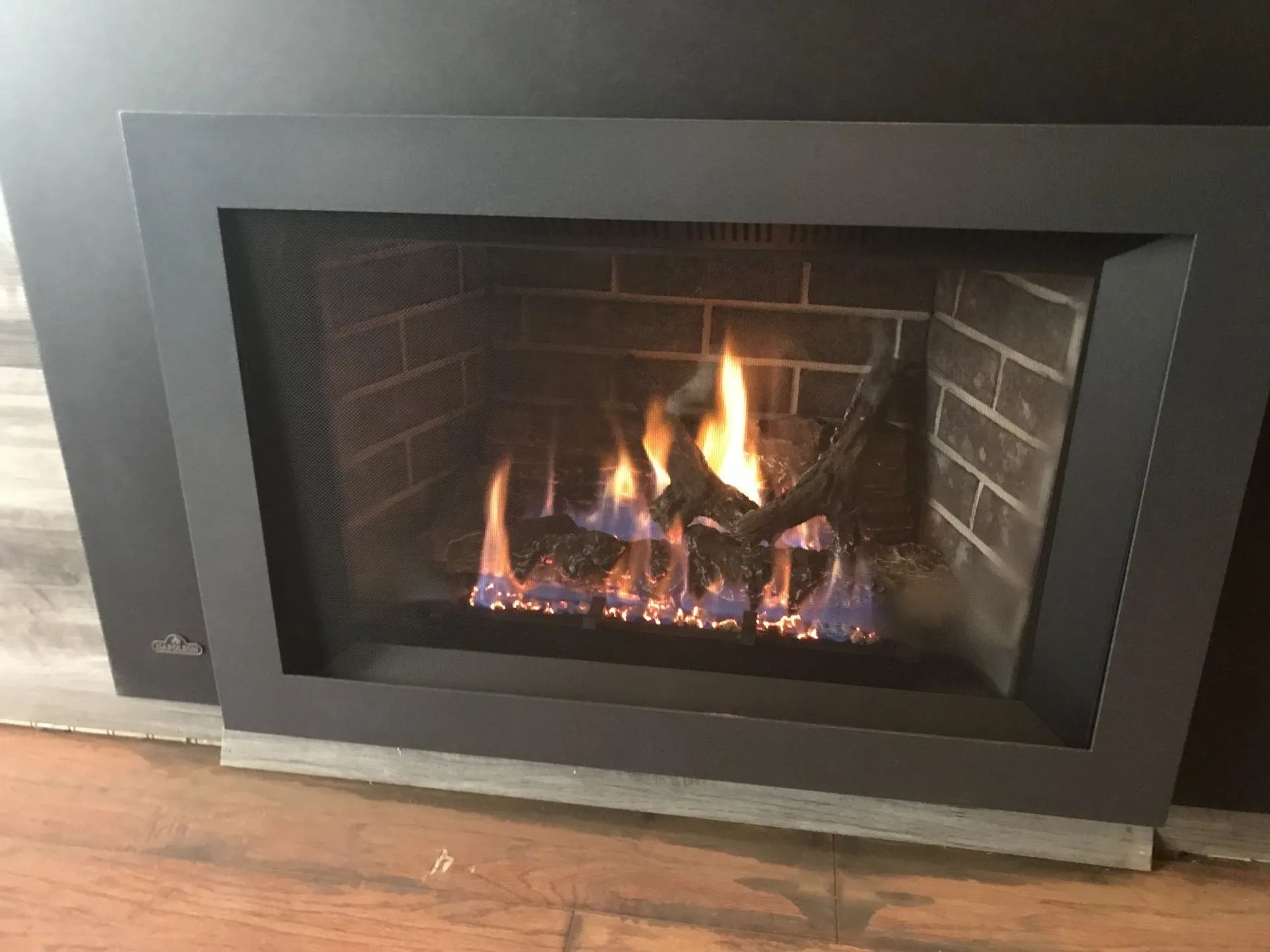 A fireplace with flames coming out of it is sitting on a wooden floor.