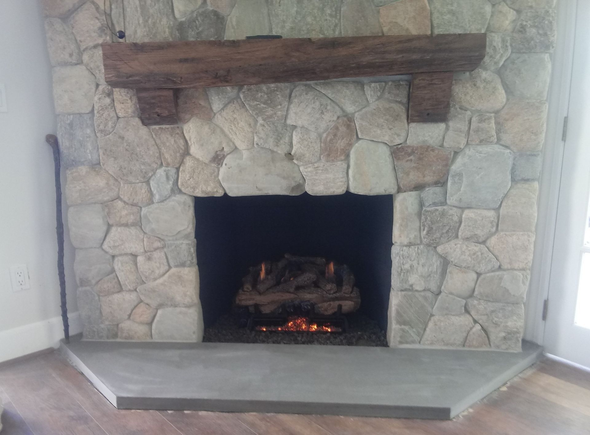A stone fireplace with a wooden mantle in a living room.