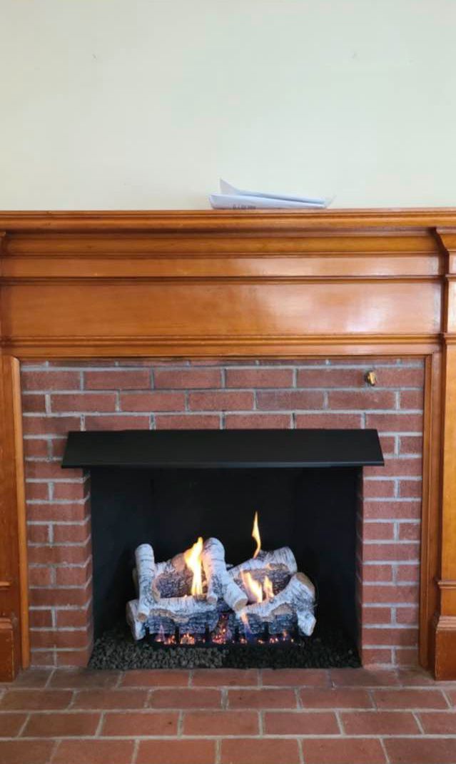 A brick fireplace with a wooden mantle in a living room