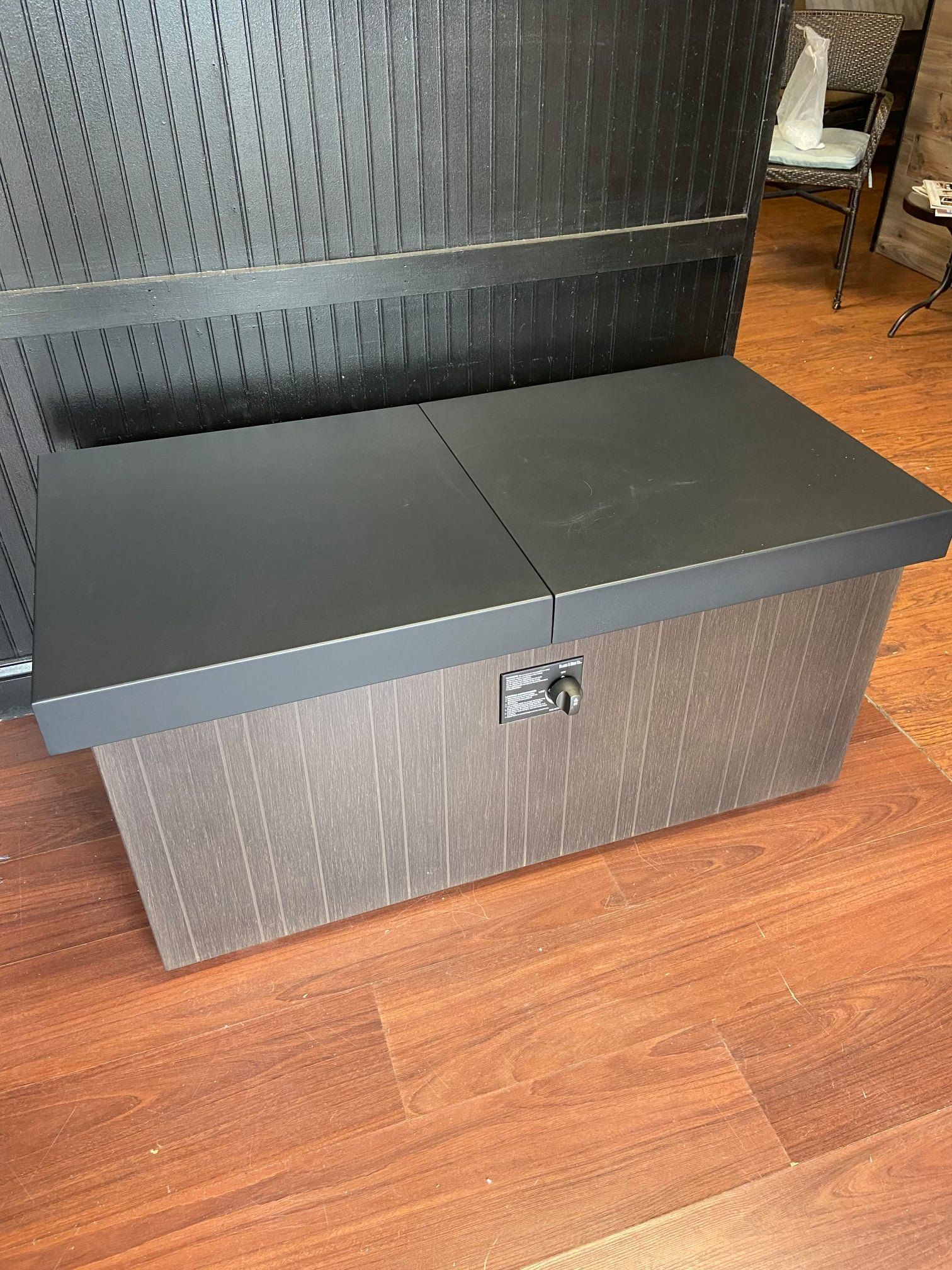 A wooden box with a black lid is sitting on a wooden floor.