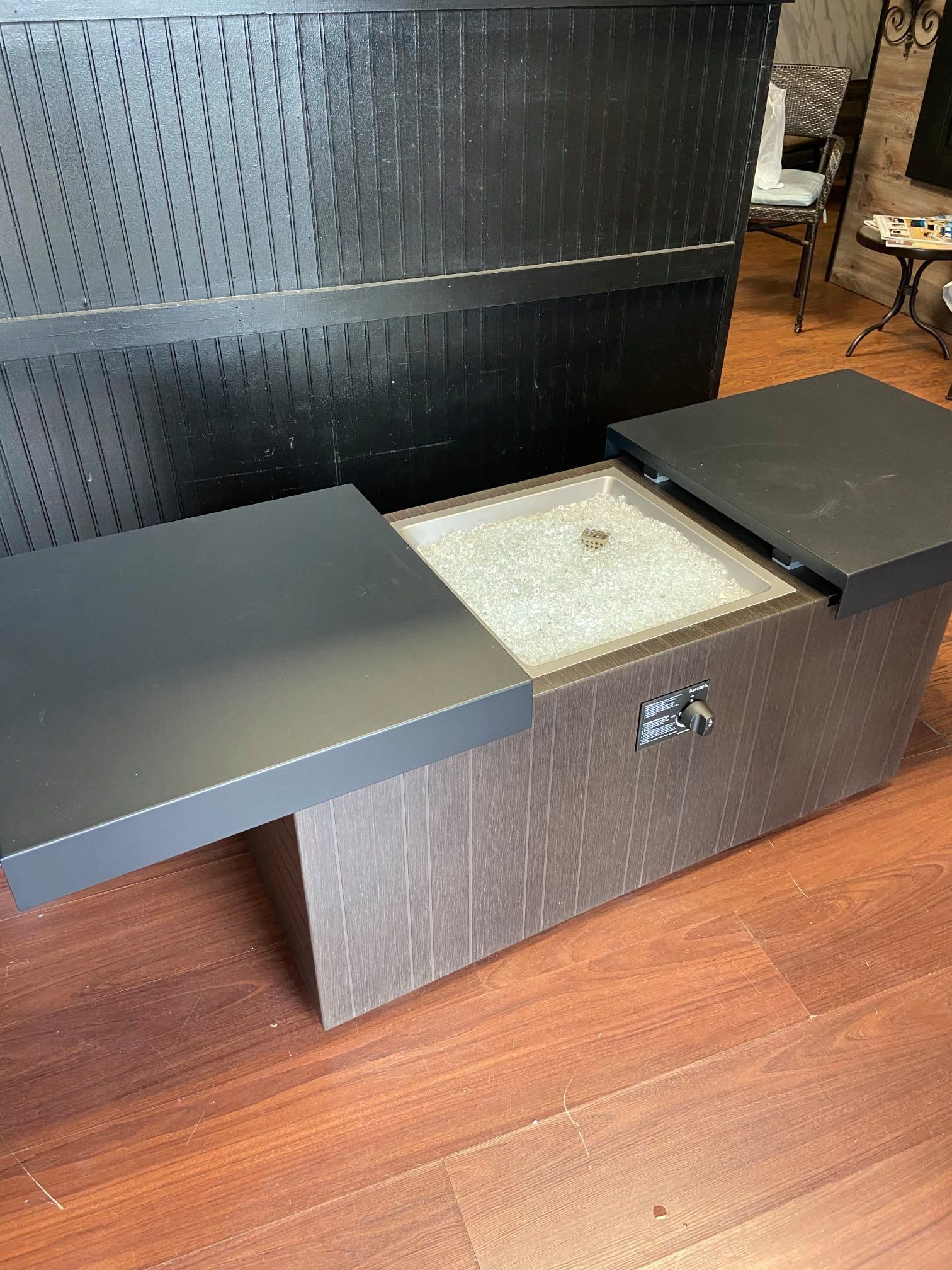 A black coffee table is sitting on a wooden floor next to a black wall.