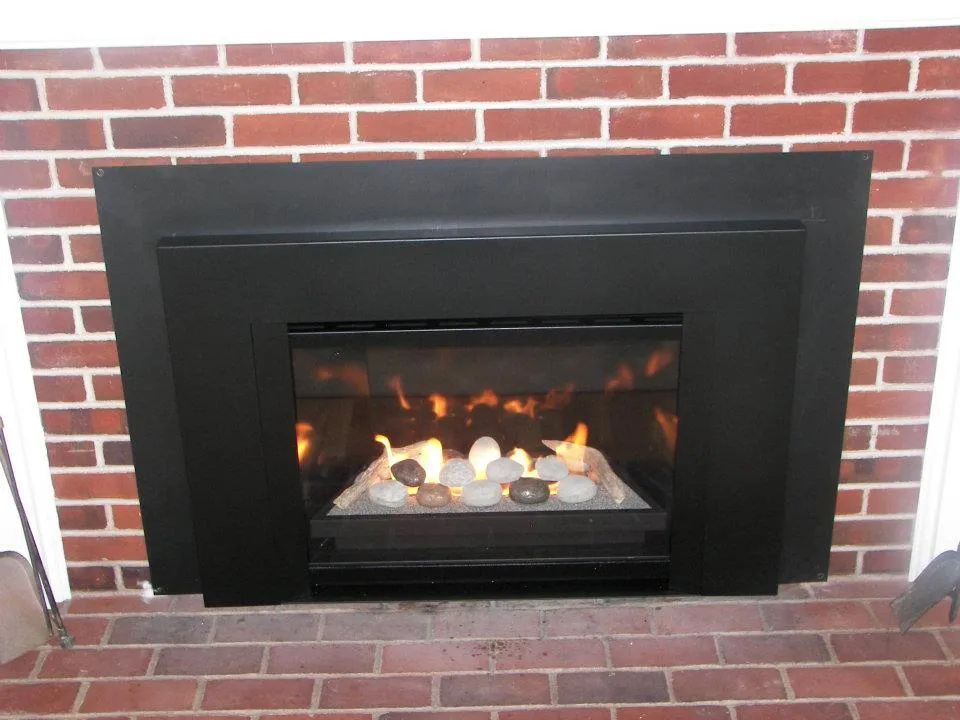 A fireplace in a brick wall with a black trim