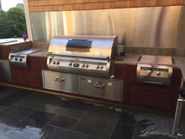 A stainless steel grill is sitting on top of a tiled floor.