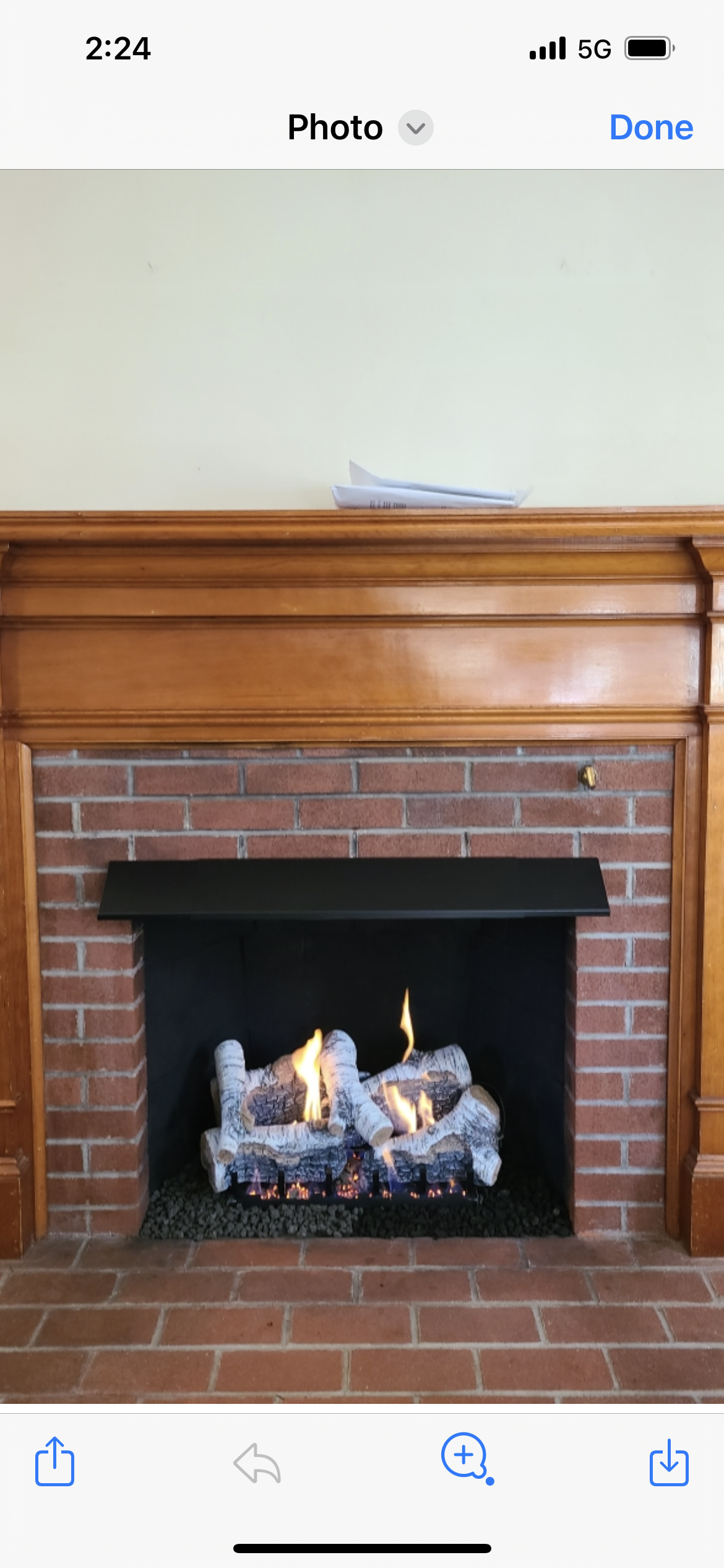 A brick fireplace with a wooden mantle in a living room.