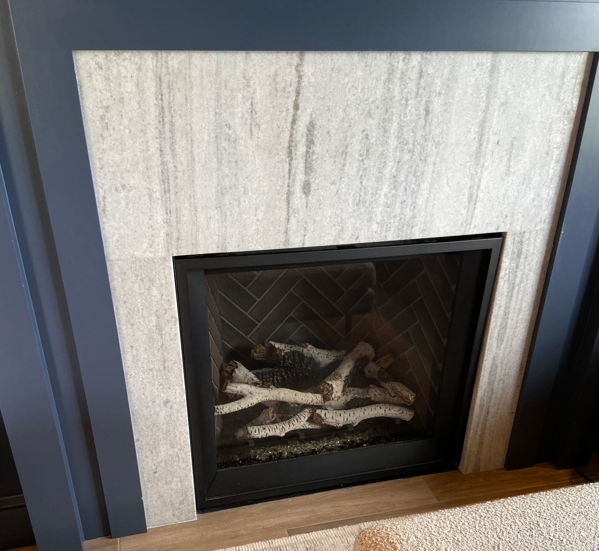 A fireplace with logs in it and a marble mantle.