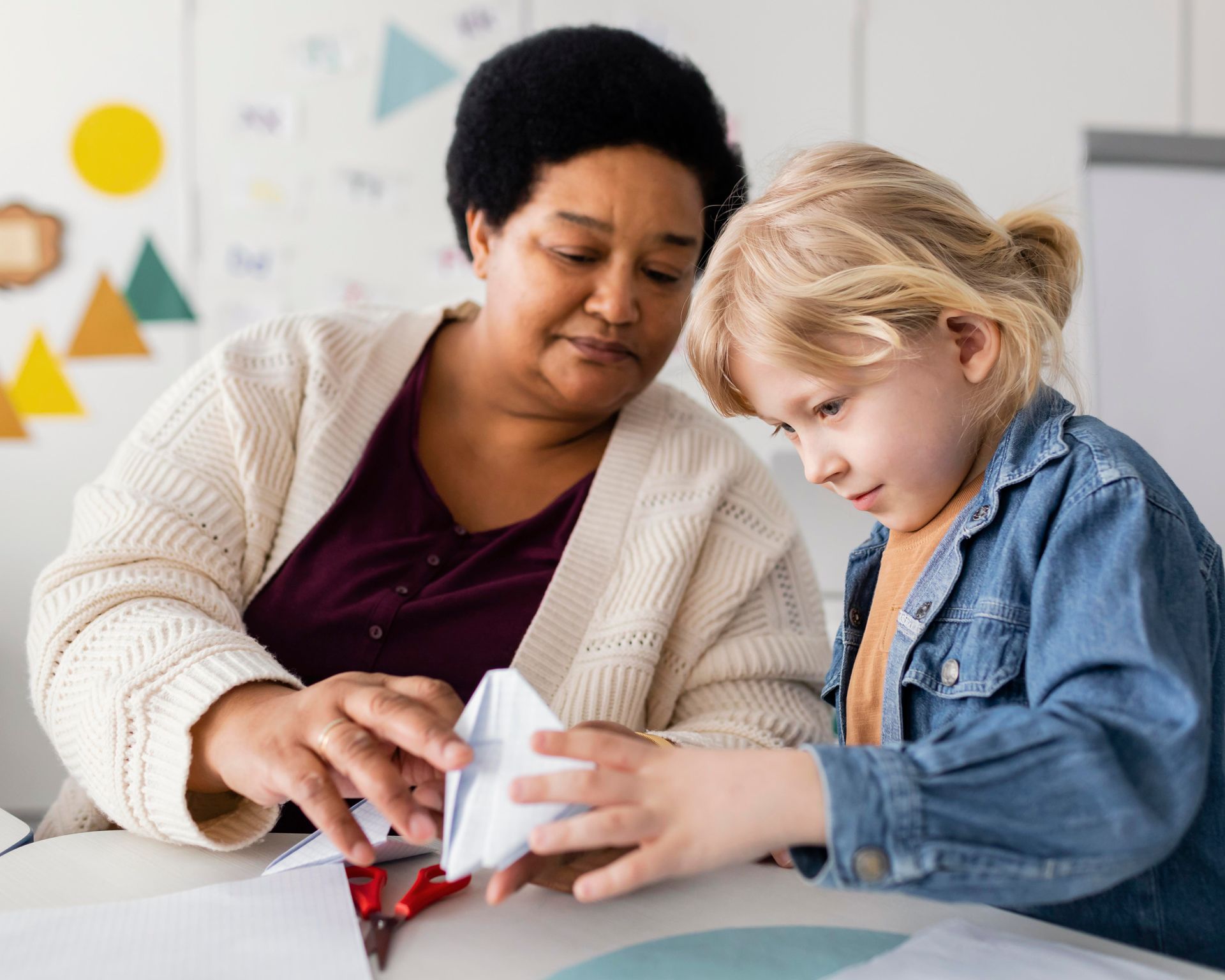 Young woman with glasses working with a small boy playing with wooden toys