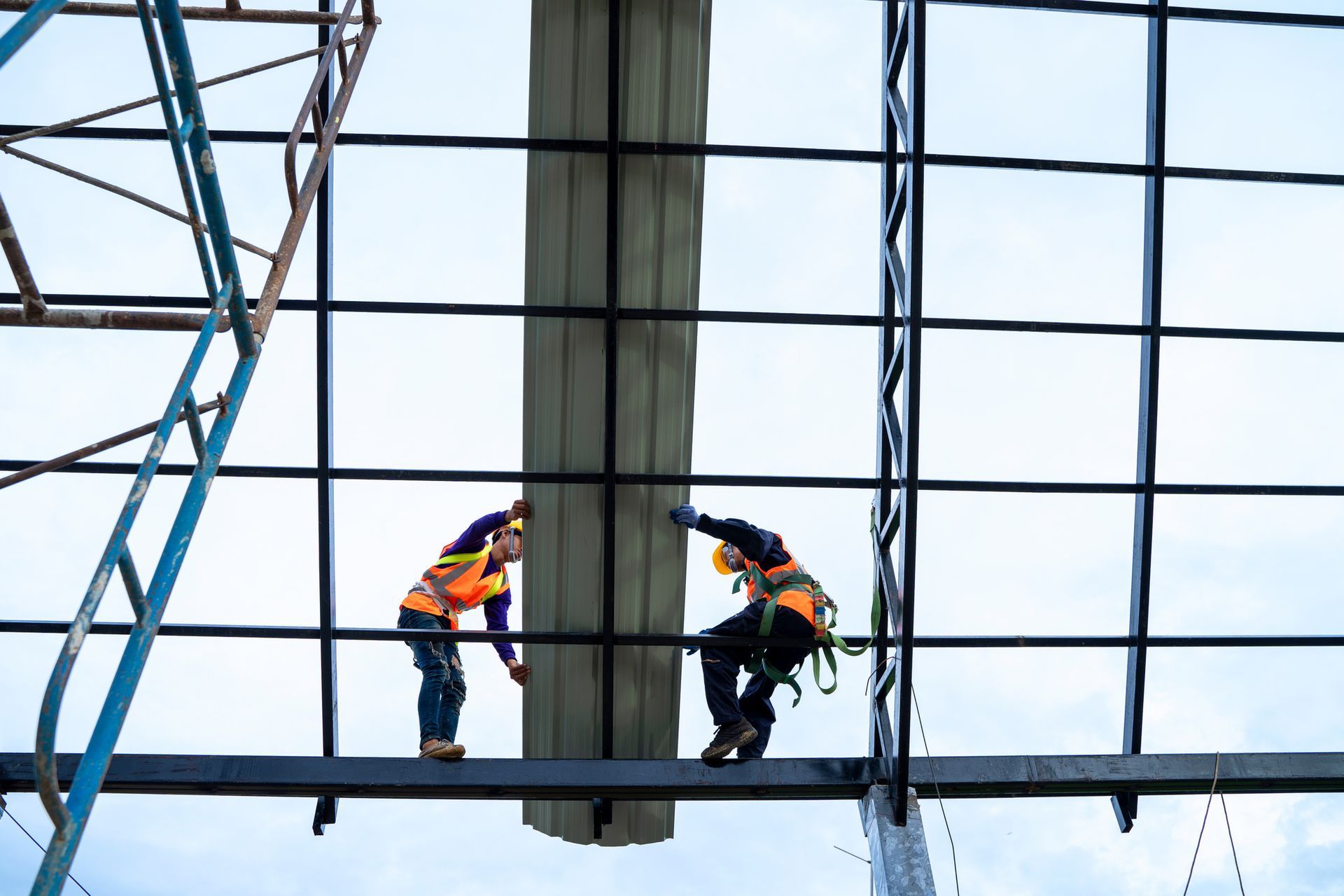 Two construction workers are standing on top of a metal structure.