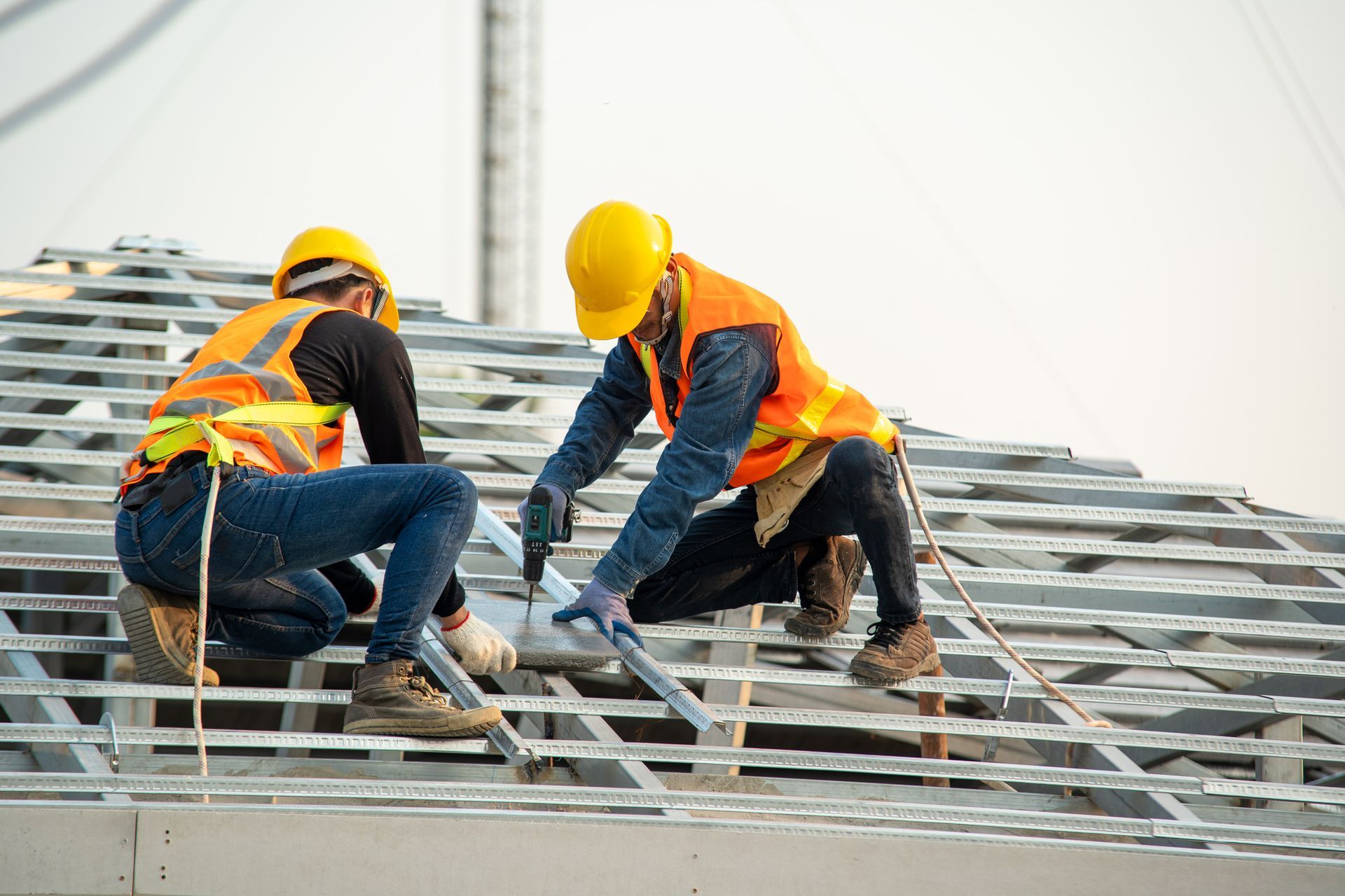 Two construction workers are working on the roof of a building.