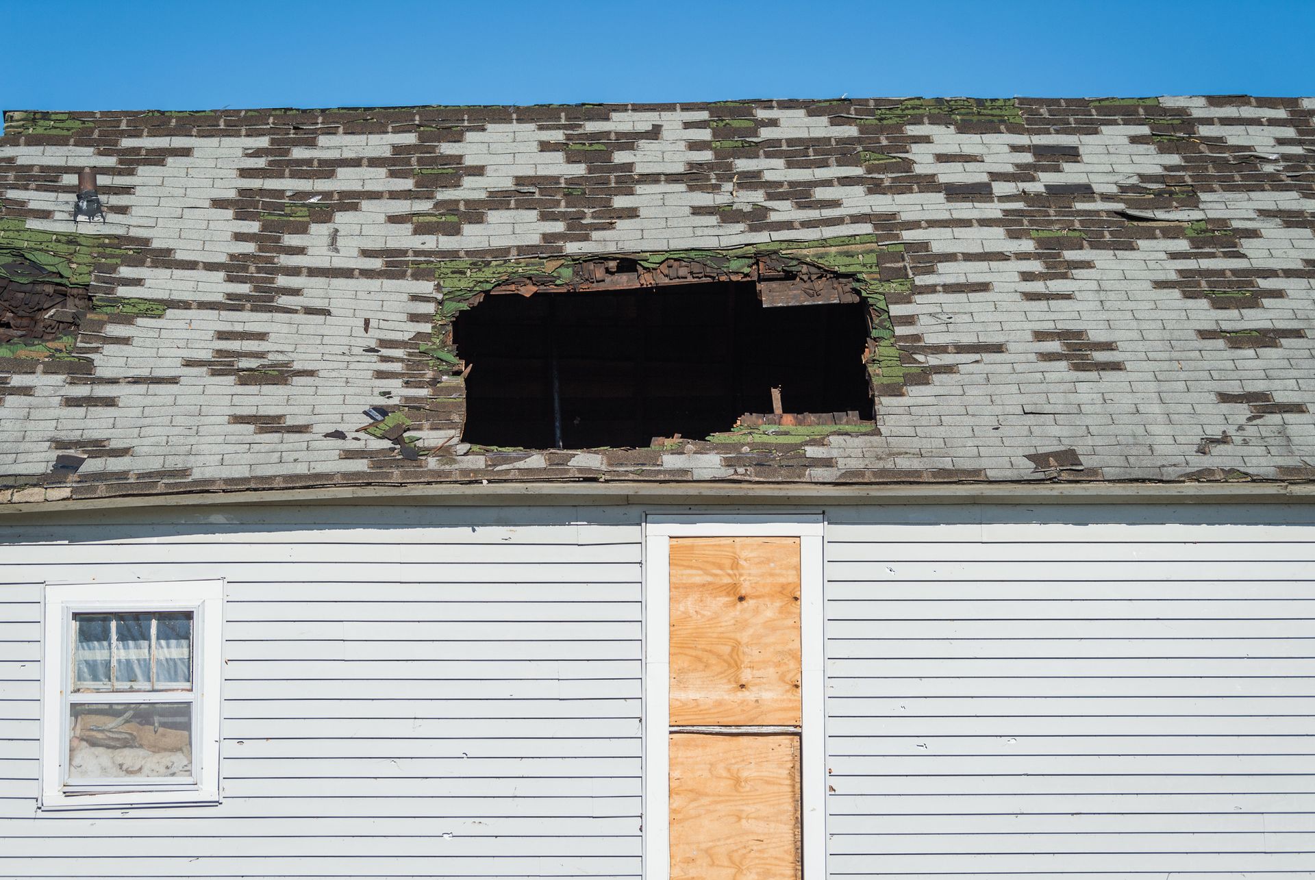 A white house with a hole in the roof and a window.