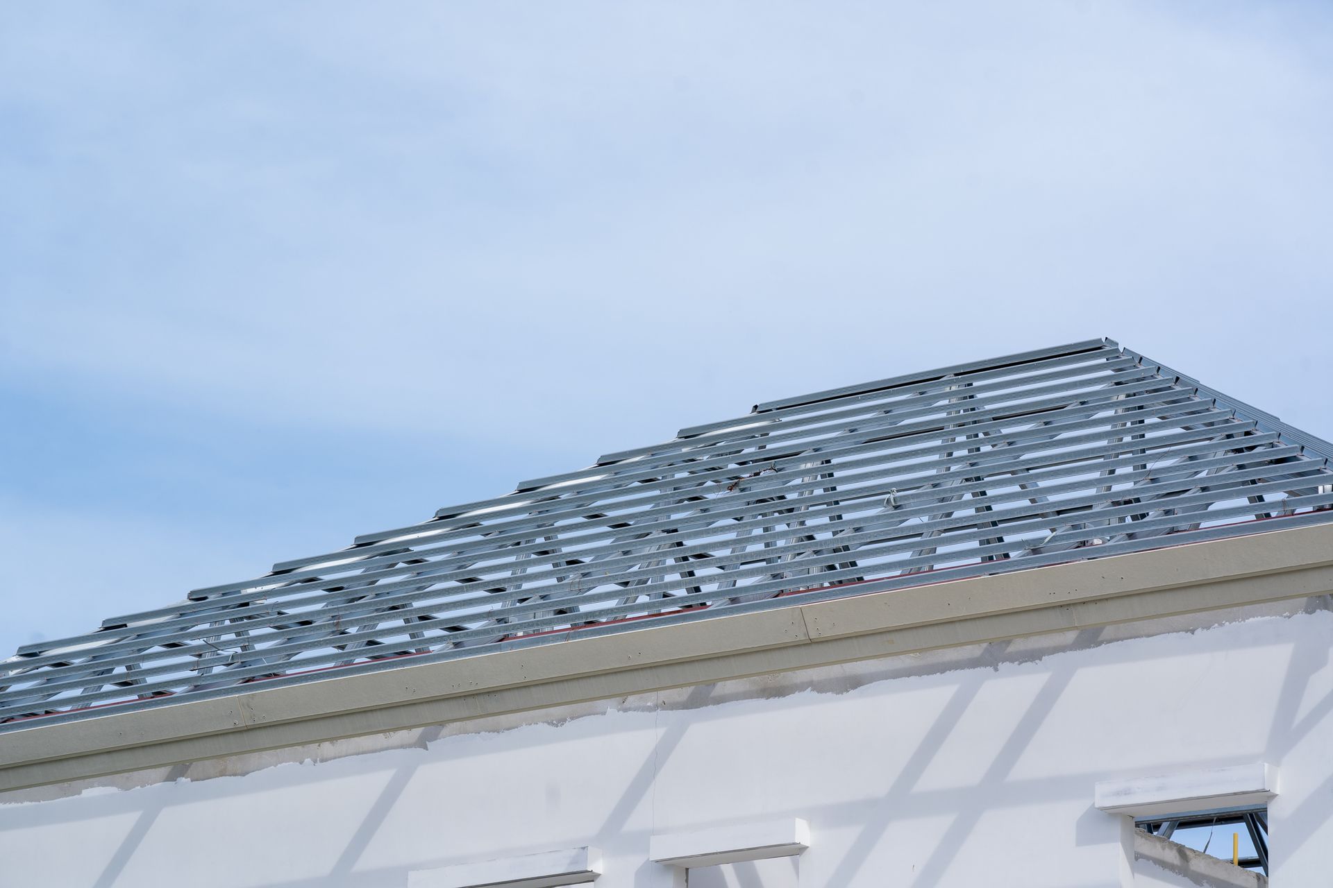 A white building with a metal roof and a blue sky in the background.