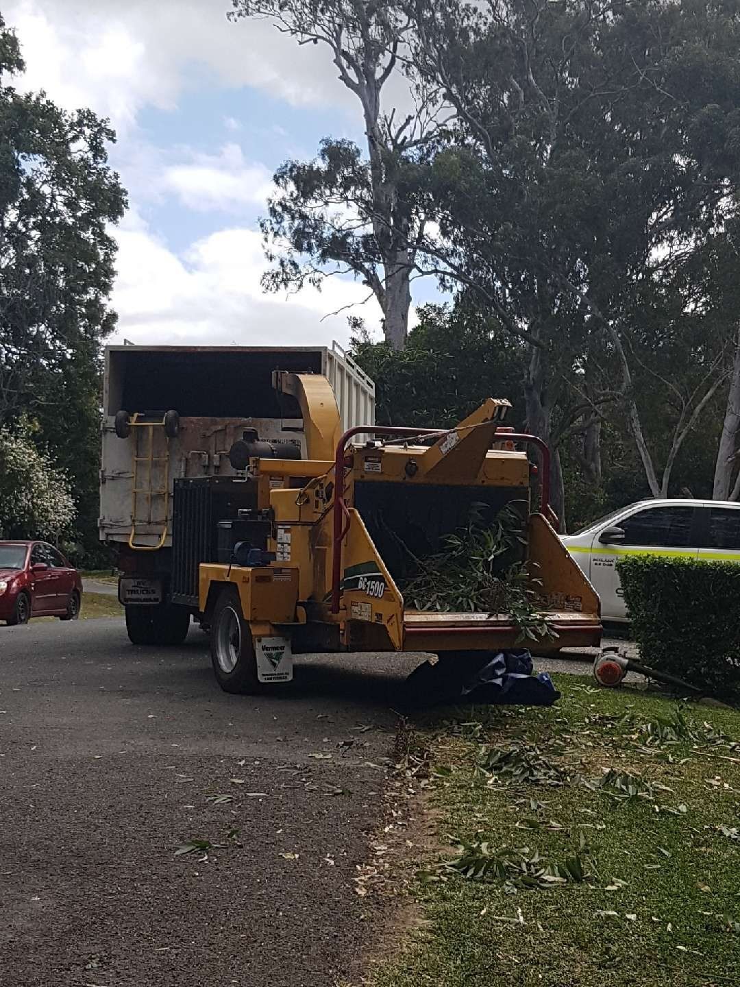 A tree chipper is parked next to a truck in a driveway.