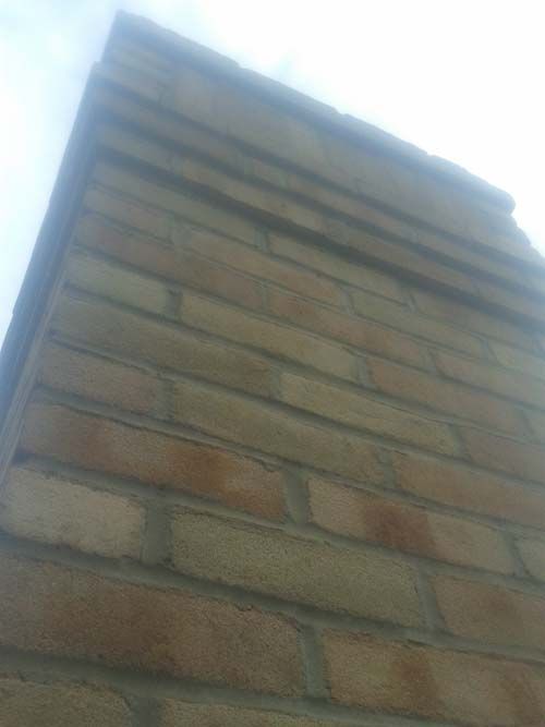 A brick wall with a chimney on top of it.