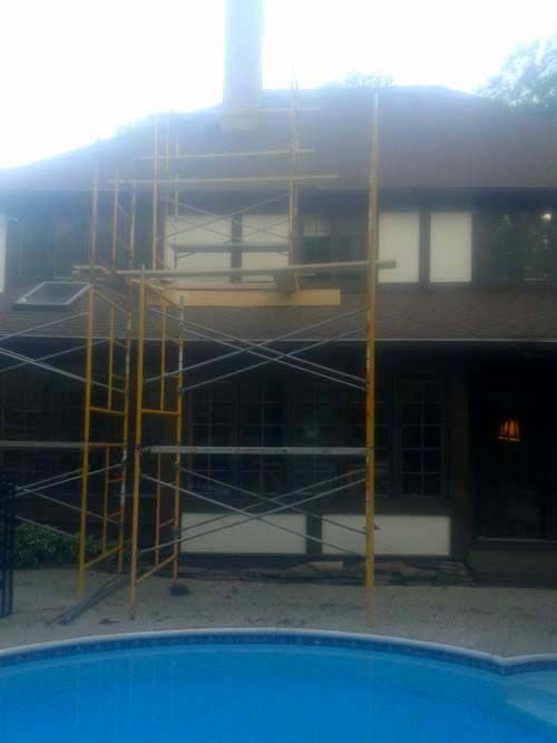 A scaffolding is sitting in front of a house next to a pool.