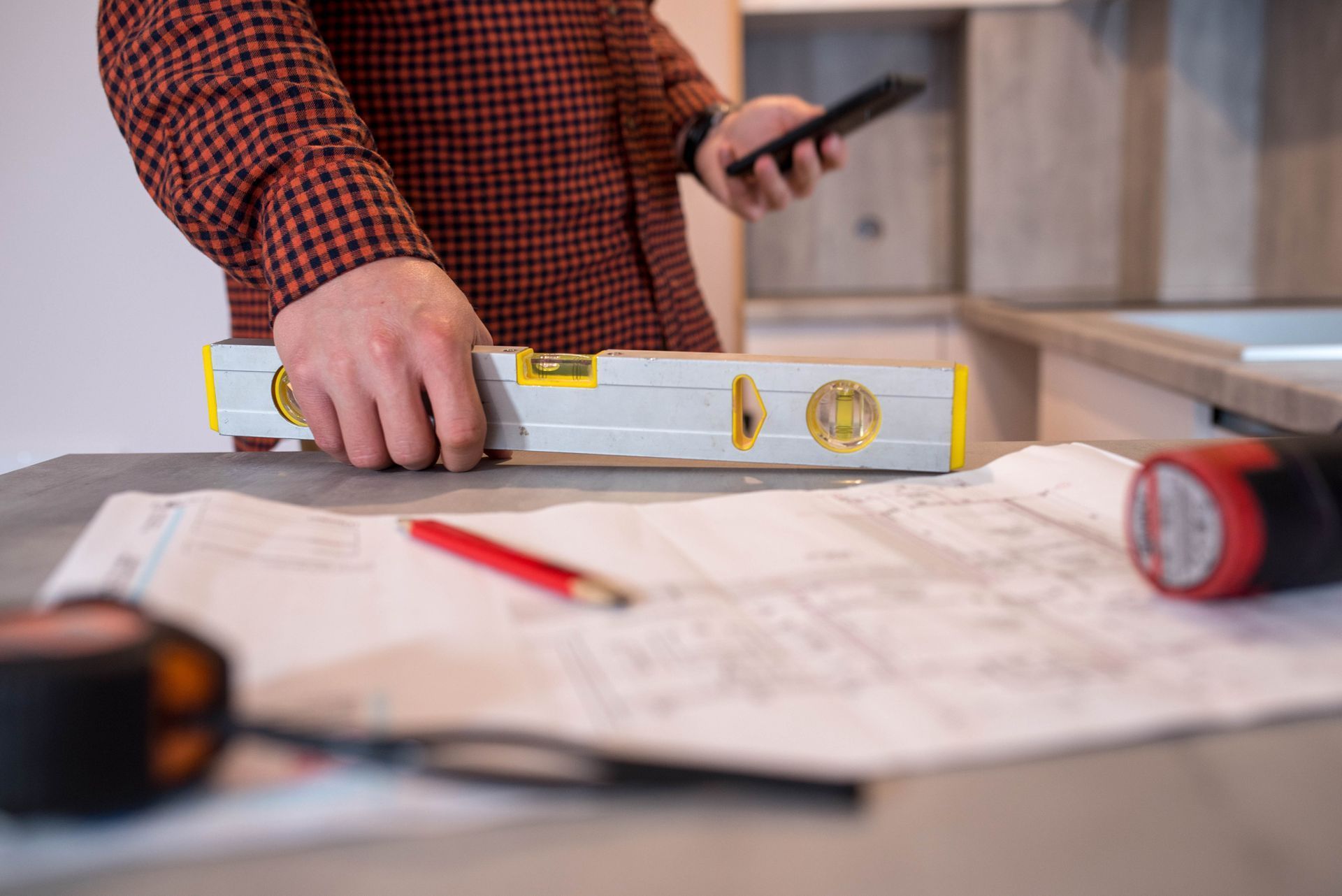 A man is using a level to measure a piece of paper on a table.