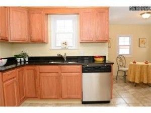 A kitchen with wooden cabinets and a stainless steel dishwasher.