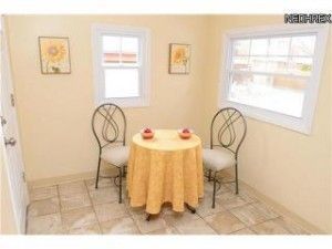 A small table with a yellow tablecloth and two chairs in a room.