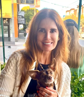 Woman smiling with a small dog in warm sunlight