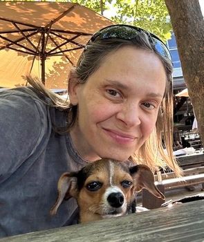 Woman smiling with a small dog in warm sunlight