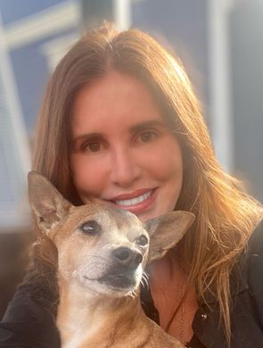 Woman smiling with a small dog in warm sunlight