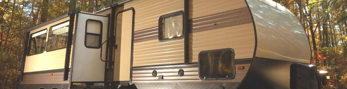 A kitchen in a camper with wooden cabinets and stainless steel appliances.