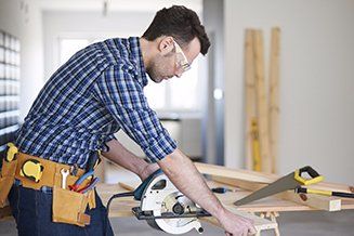 A man is using a circular saw to cut a piece of wood.
