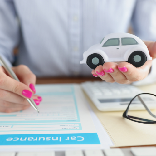 woman completing an insurance claim form holding a toy car in the other hand