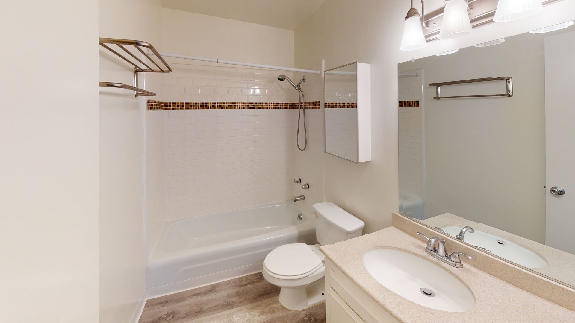 Bathroom with white fixtures, vanity, toilet, and shower/tub combo; neutral color palette.