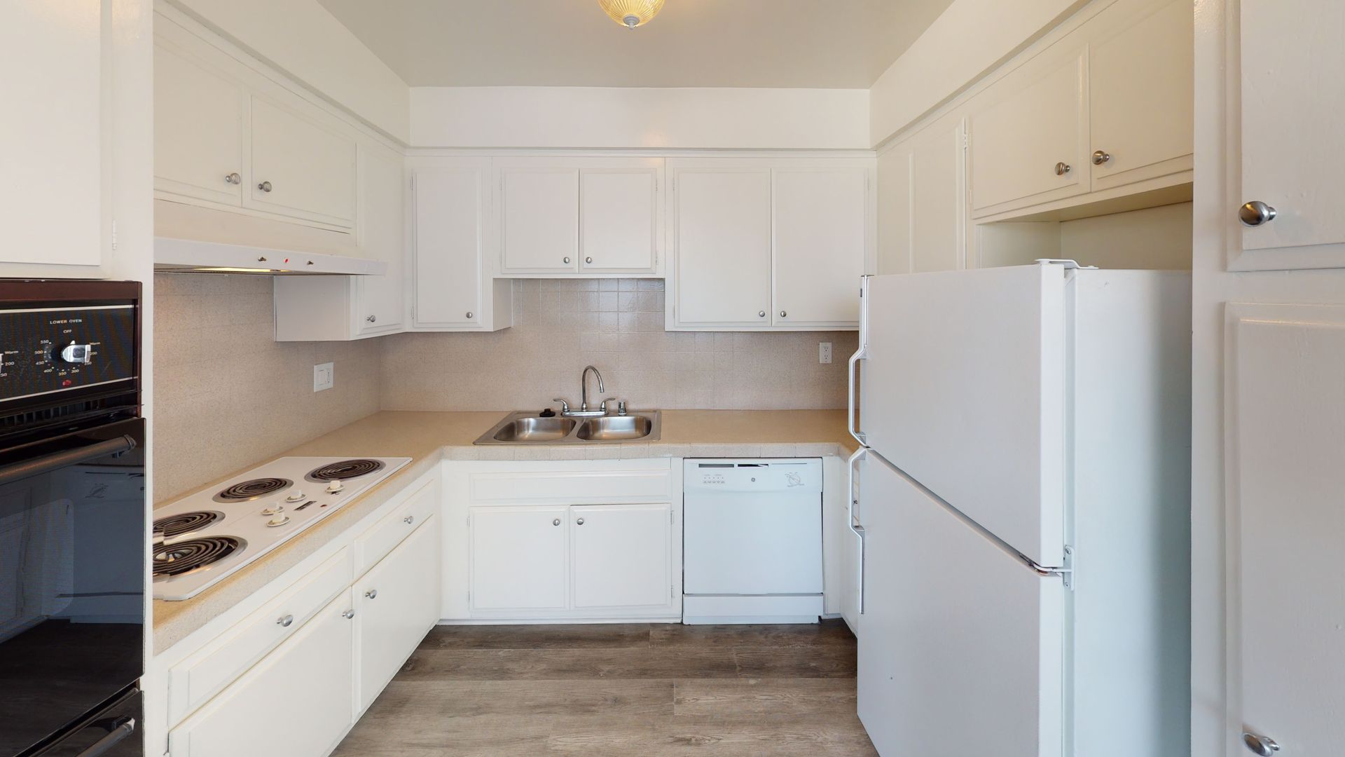 White kitchen with cabinets, appliances, and a cooktop.