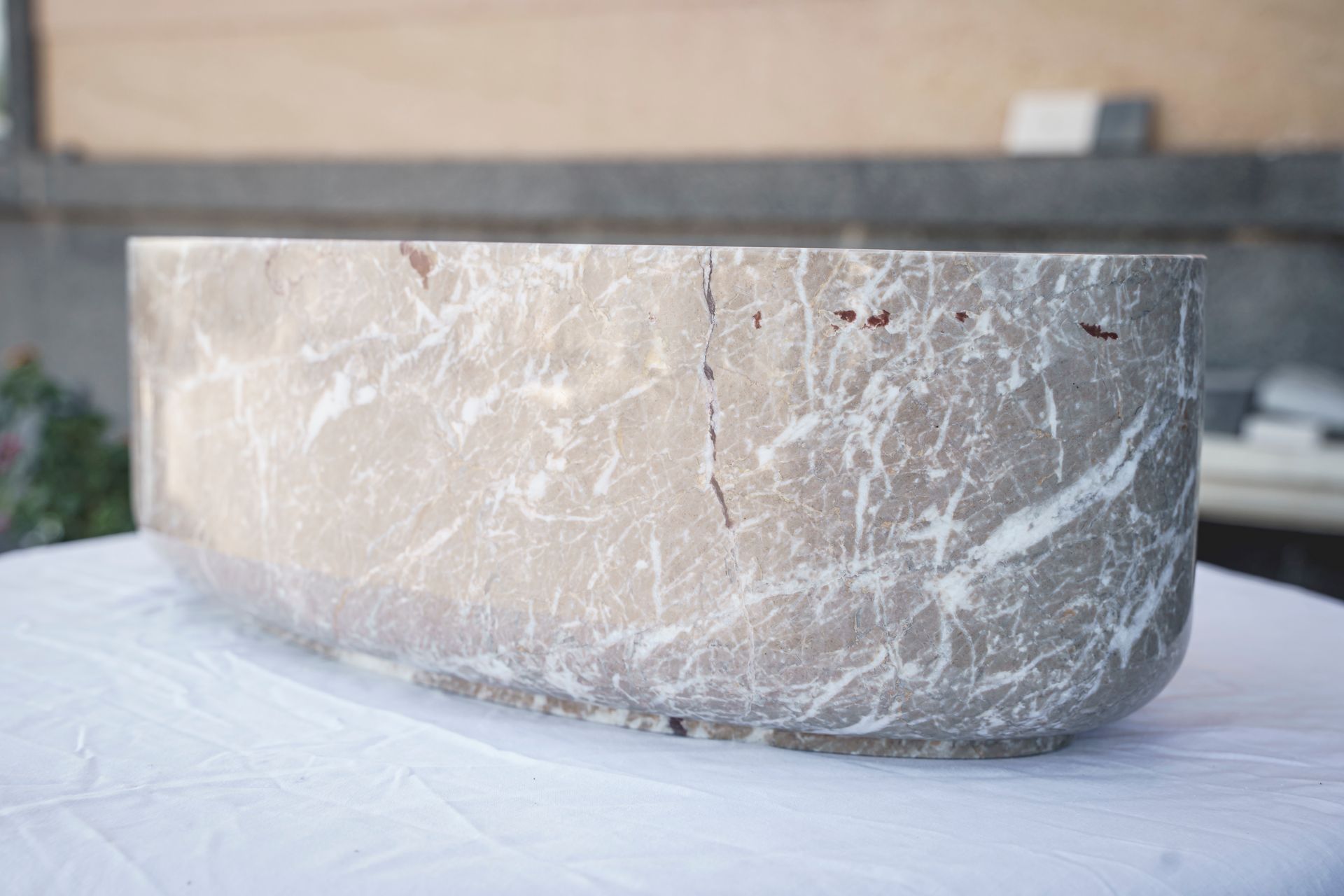 Recipiente rettangolare in marmo con angoli arrotondati, appoggiato su una superficie bianca, all'aperto.