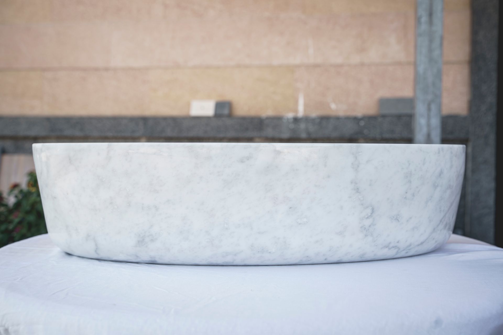 Bacinella rotonda in marmo bianco su tovaglia bianca.