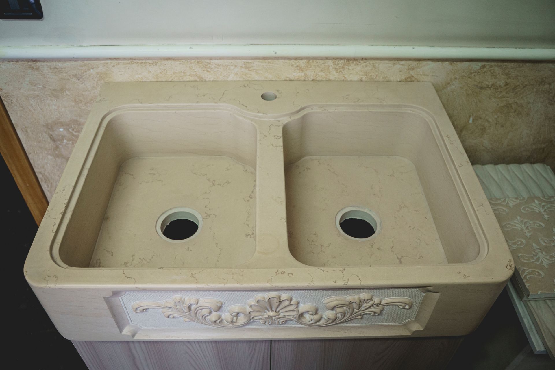 Lavello da cucina beige a doppia vasca con dettagli floreali in rilievo.