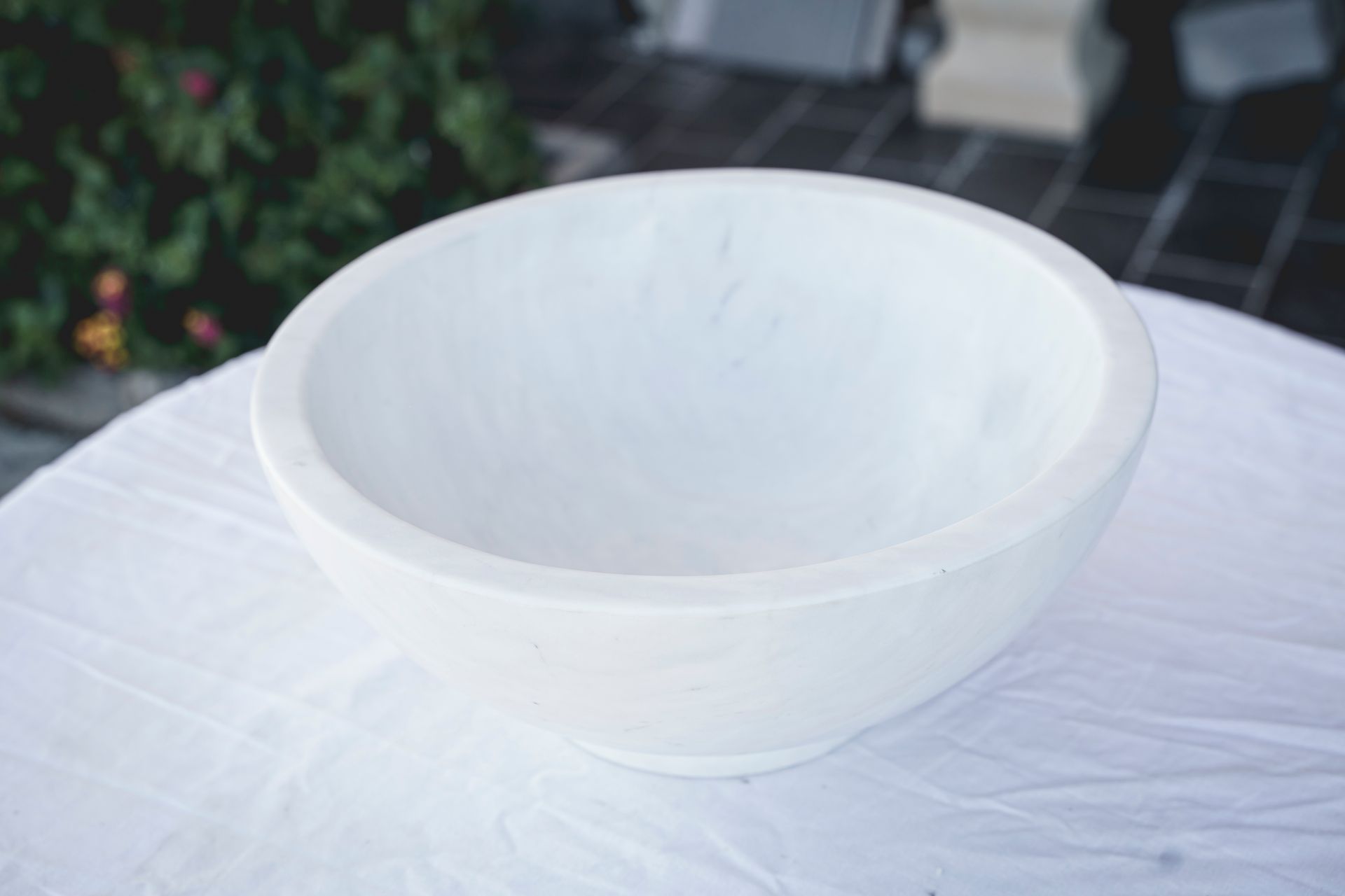 Ciotola in ceramica bianca su una tovaglia bianca all'aperto.