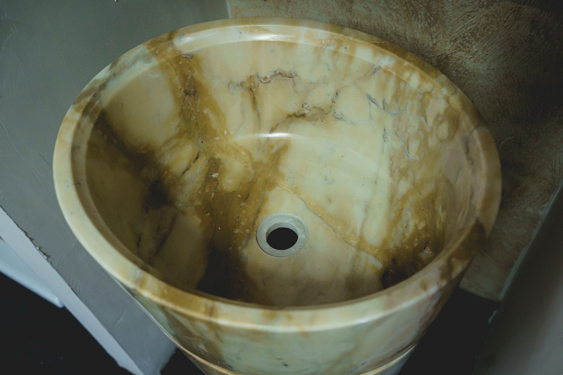 Lavandino rotondo in marmo beige con foro di scarico.