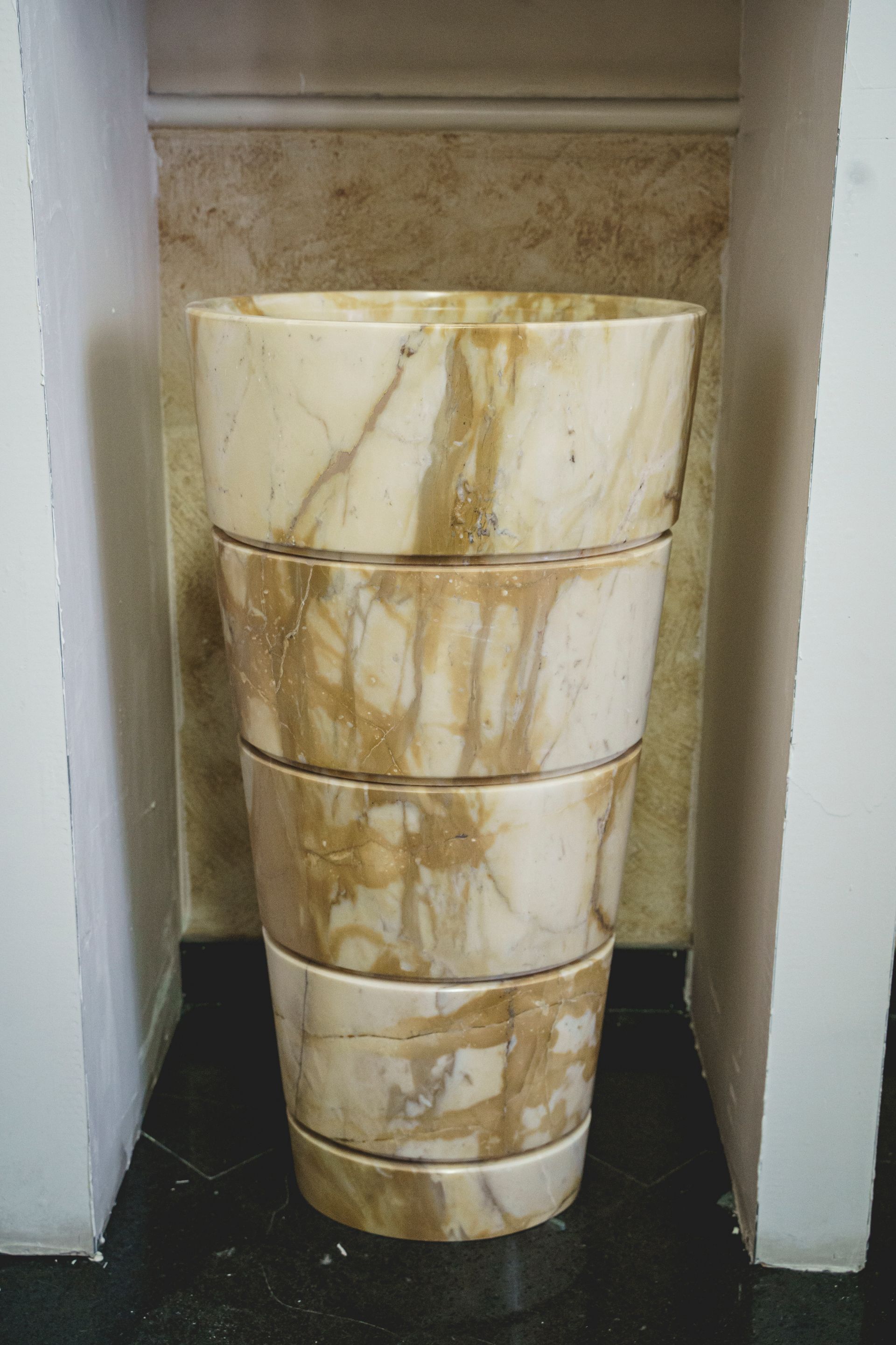 Contenitori di marmo impilati all'interno di una nicchia incassata, con venature beige e marroni.