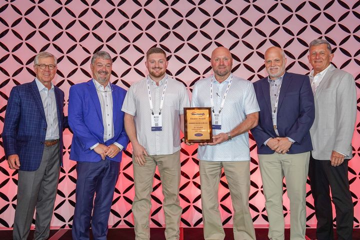 A homeowner shakes hands with an HVAC technician near a unit outside a house.
