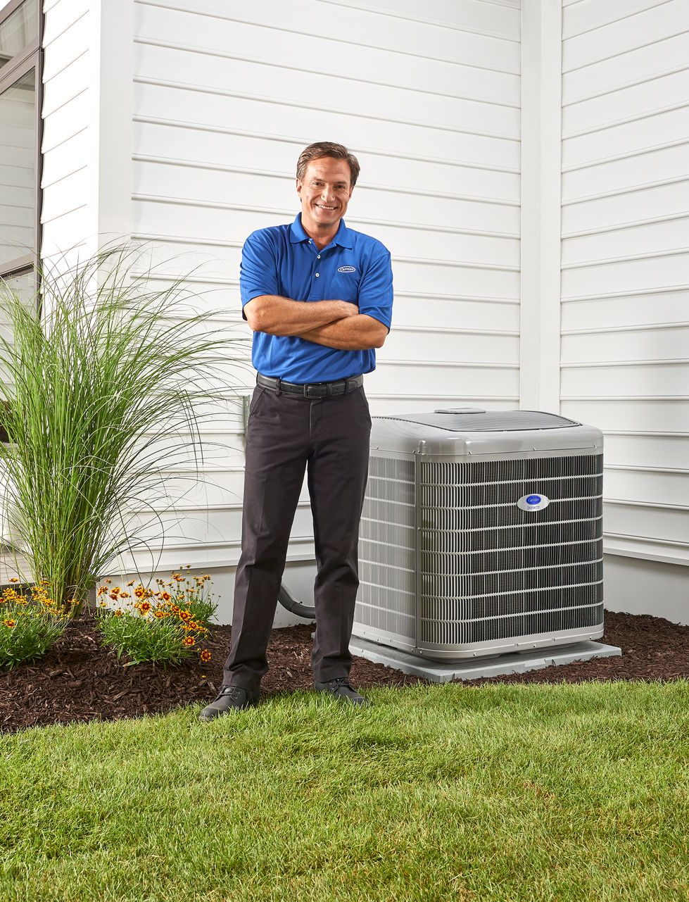 Carrier HVAC technician with van and furnace.