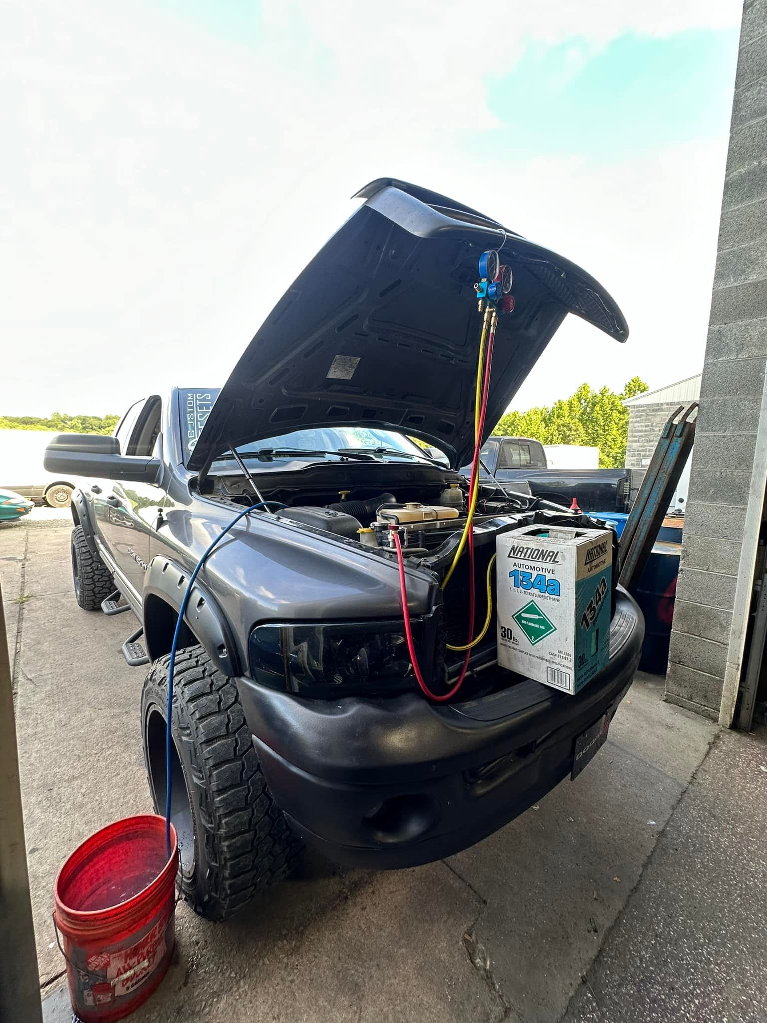 A truck with the hood up is being worked on in a garage.